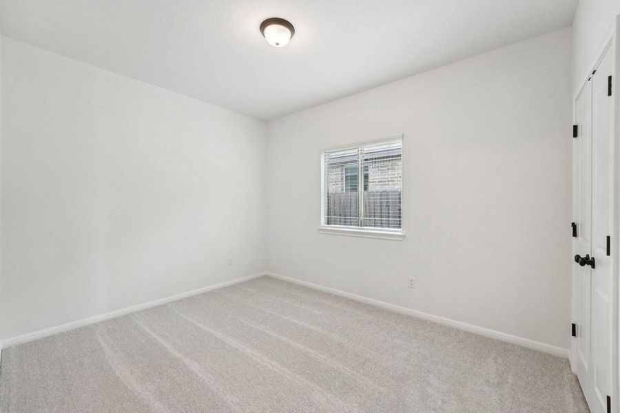 A well-lit bedroom features plush carpet flooring and a window offering natural illumination. A well-lit bedroom features plush carpet flooring and a window offering natural illumination.