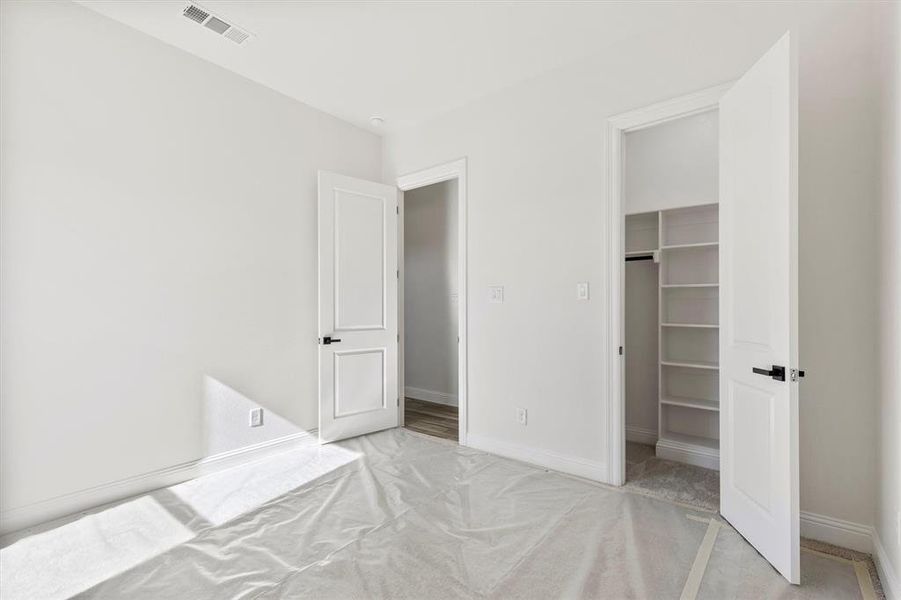 Bedroom with a walk in closet, carpet, and a closet