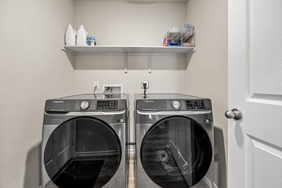 Functional laundry space featuring modern appliances and convenient overhead shelving.