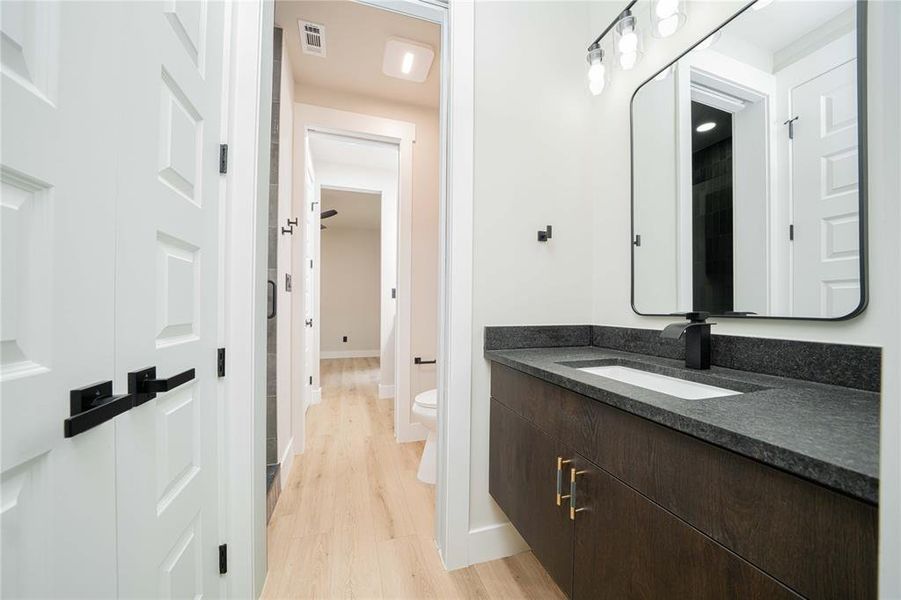 Floating vanity with dark wood-finish cabinetry, a dark speckled countertop, and an integrated rectangular sink