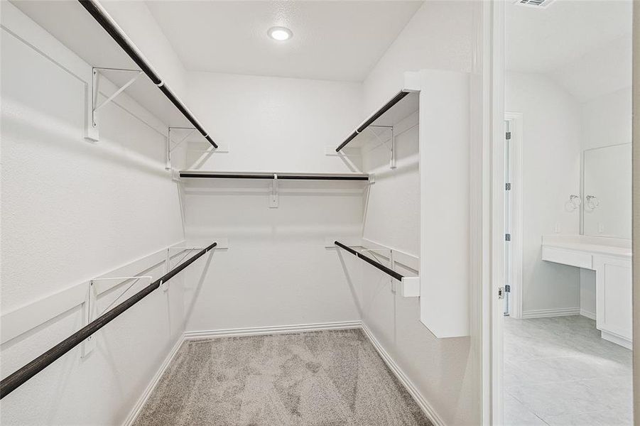 Walk in closet with vaulted ceiling and light carpet