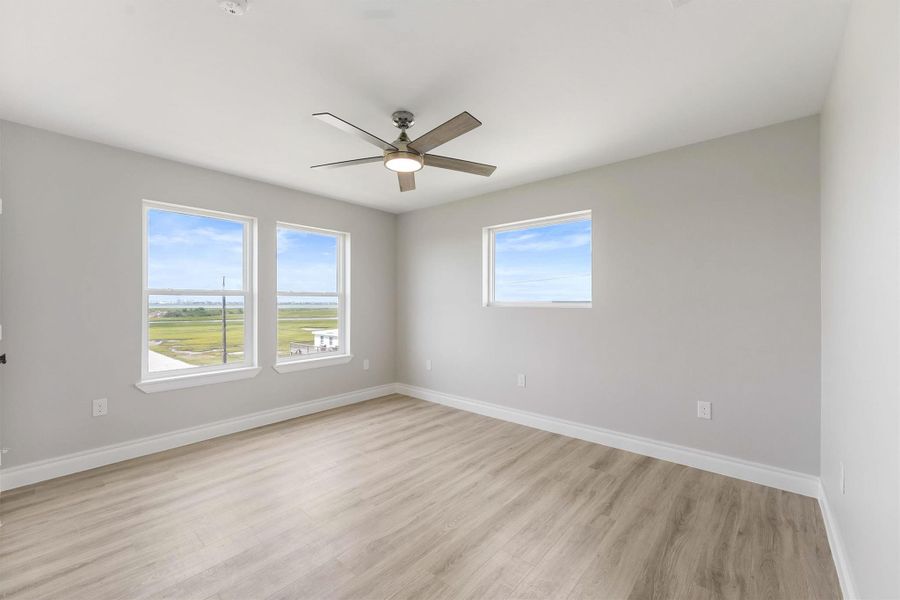 Bright and airy room with large windows offering scenic views, light wood flooring, neutral walls, and a modern ceiling fan. Bright and airy room with large windows offering scenic views, light wood flooring, neutral walls, and a modern ceiling fan.