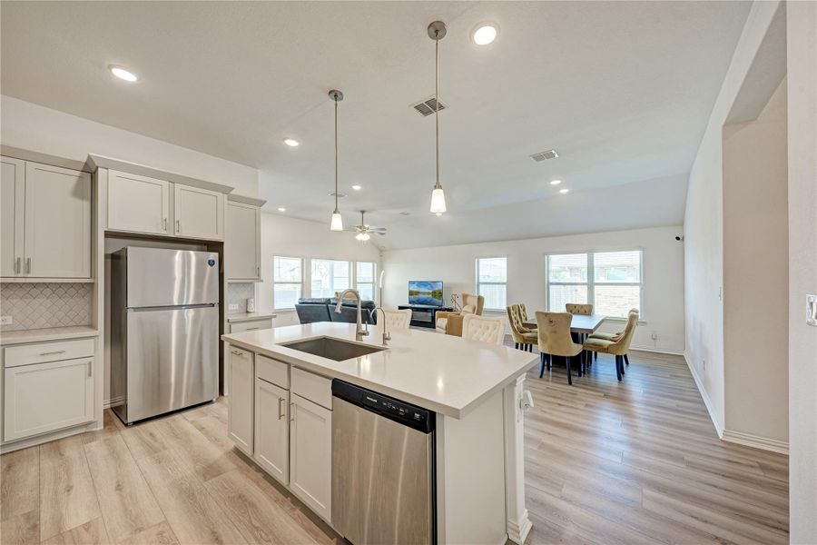 An open-concept layout showcases a kitchen island with seating, a living area, and a dining space with numerous windows.