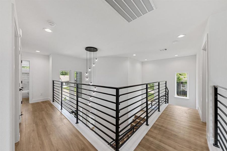 This property features an open landing area with hardwood floors, contemporary black metal railings, and recessed lighting This property features an open landing area with hardwood floors, contemporary black metal railings, and recessed lighting