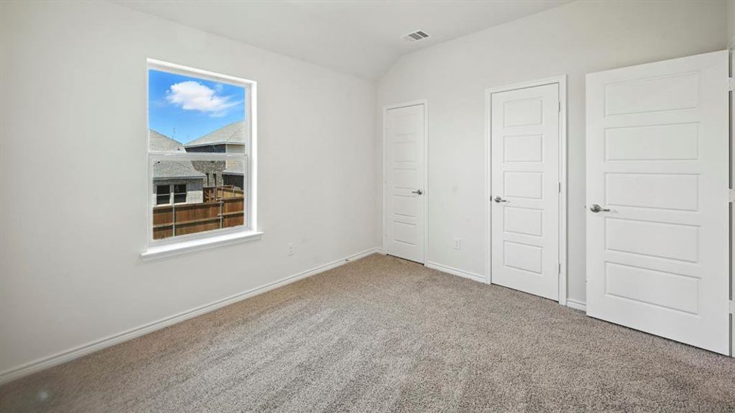 Unfurnished bedroom with carpet floors and lofted ceiling
