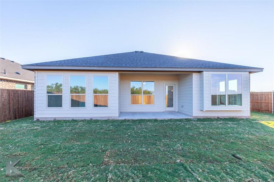 Back of property featuring a fenced backyard, a patio area, and a shingled roof