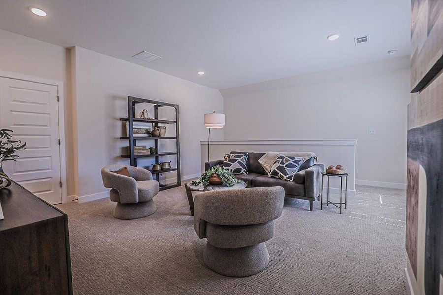 Living area with light colored carpet and recessed lighting