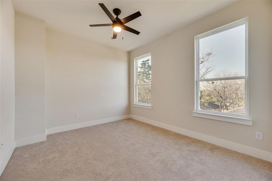Empty room with light colored carpet and a ceiling fan Empty room with light colored carpet and a ceiling fan