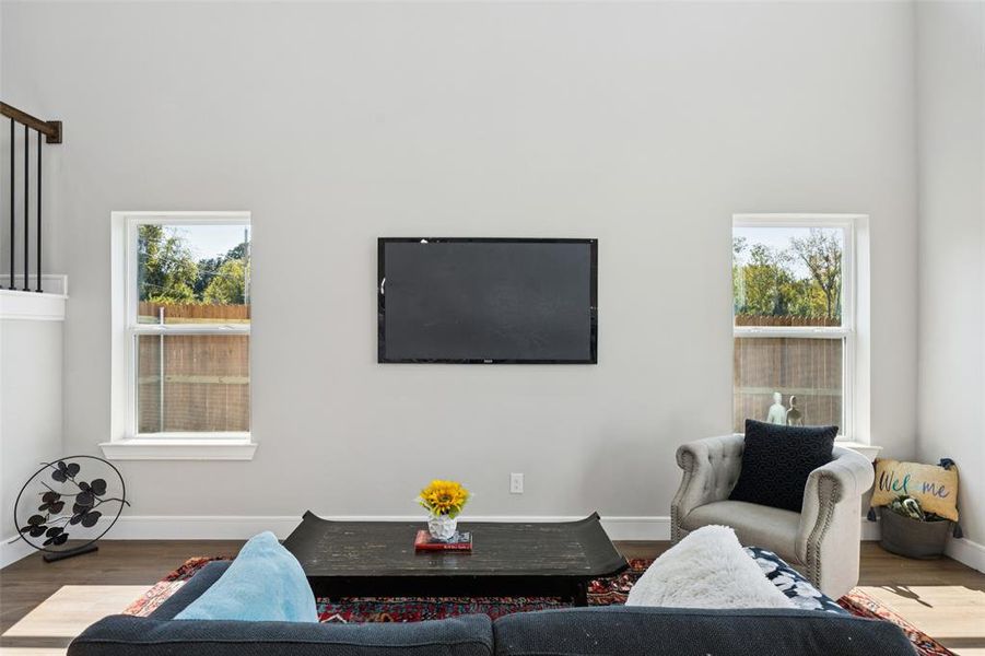 Living area featuring wood finished floors, plenty of natural light, and a high ceiling