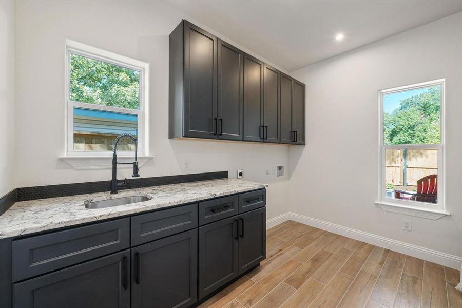 Laundry area featuring washer hookup, wood finish floors, cabinet space, hookup for an electric dryer, and recessed lighting Laundry area featuring washer hookup, wood finish floors, cabinet space, hookup for an electric dryer, and recessed lighting
