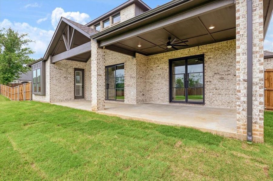 Rear view of property featuring a patio, a yard, and ceiling fan