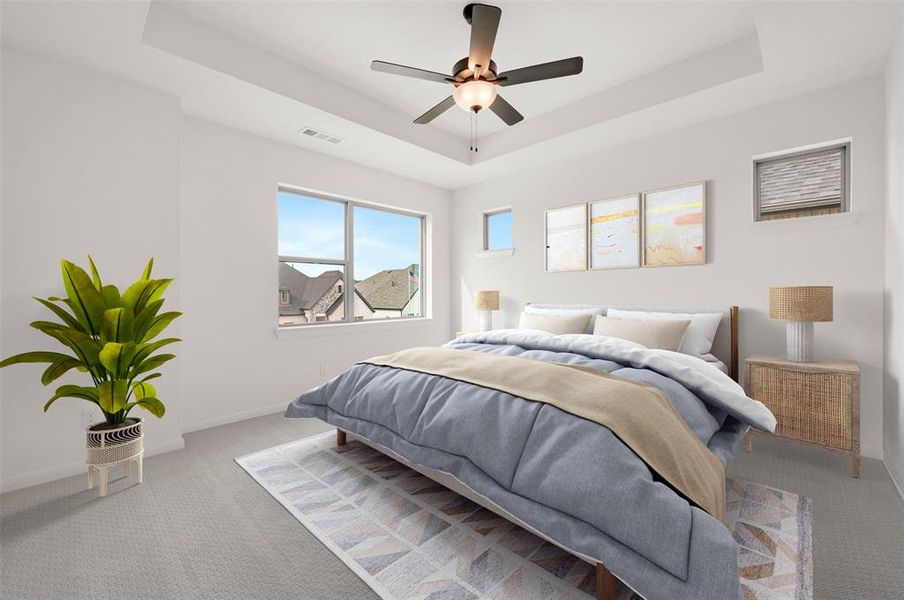 Bedroom featuring a tray ceiling, carpet floors, and a ceiling fan