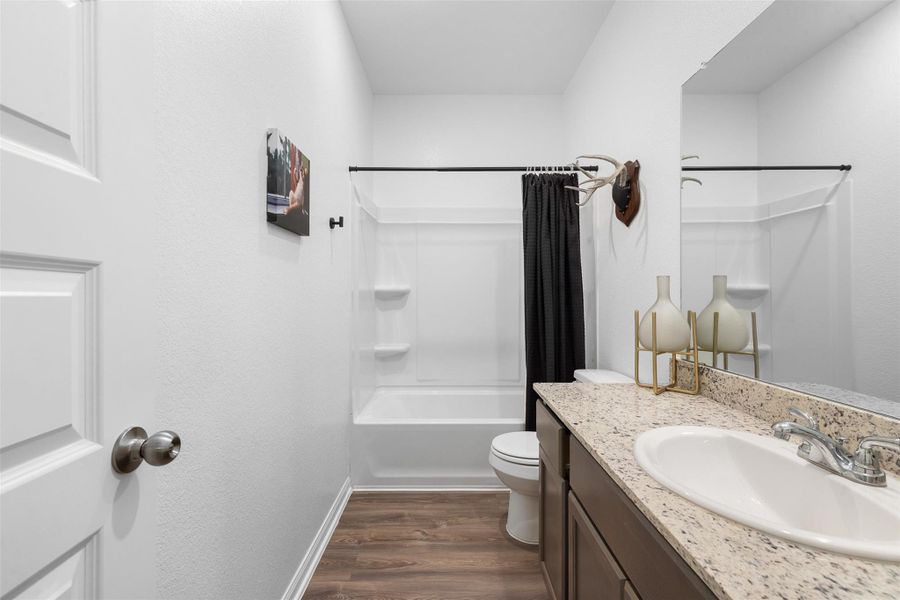 Elegant hall bathroom featuring a sleek granite countertop, stylish fixtures, and a modern shower/tub combo