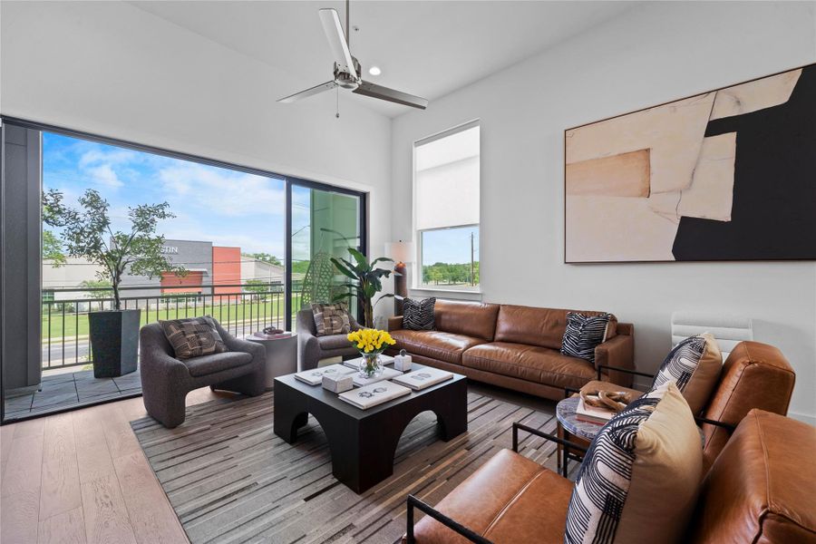 Living area featuring high ceilings, wood-finish flooring, and a sliding glass door opening to a balcony