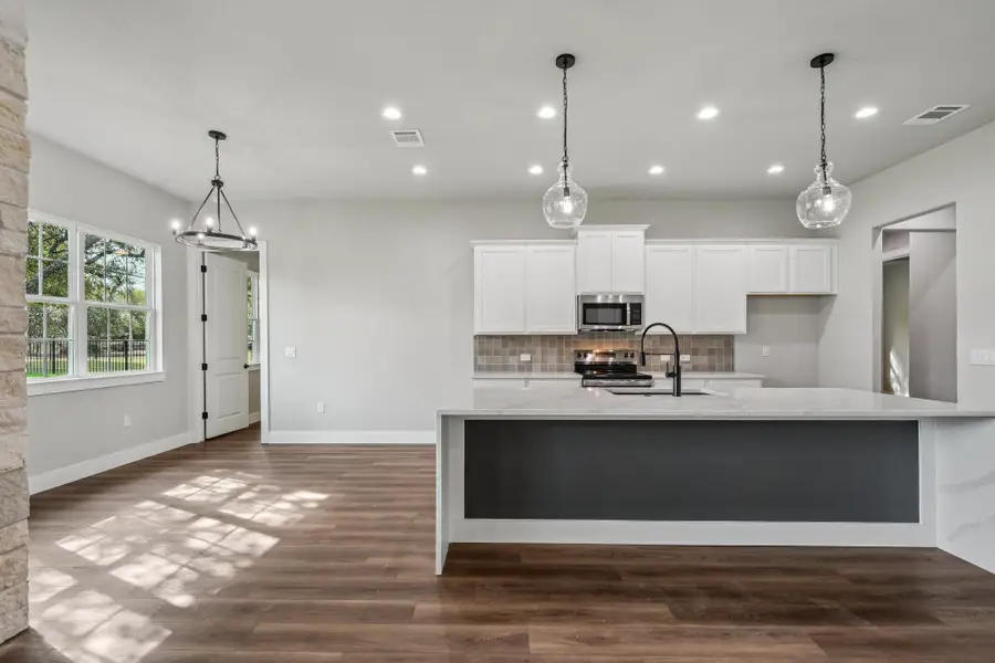 Kitchen with white cabinets, backsplash, light stone countertops, pendant lighting, and recessed lighting