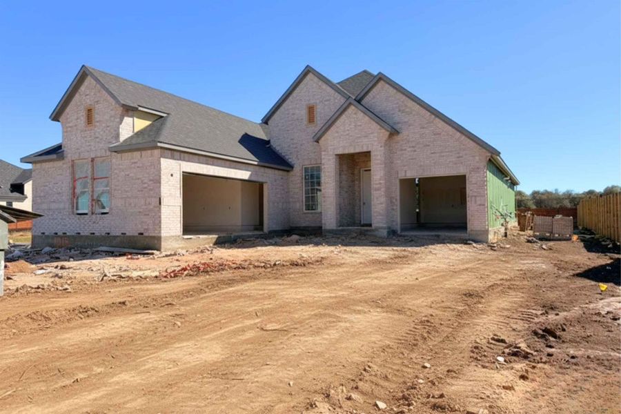 View of front of house featuring a garage, dirt driveway, and brick siding