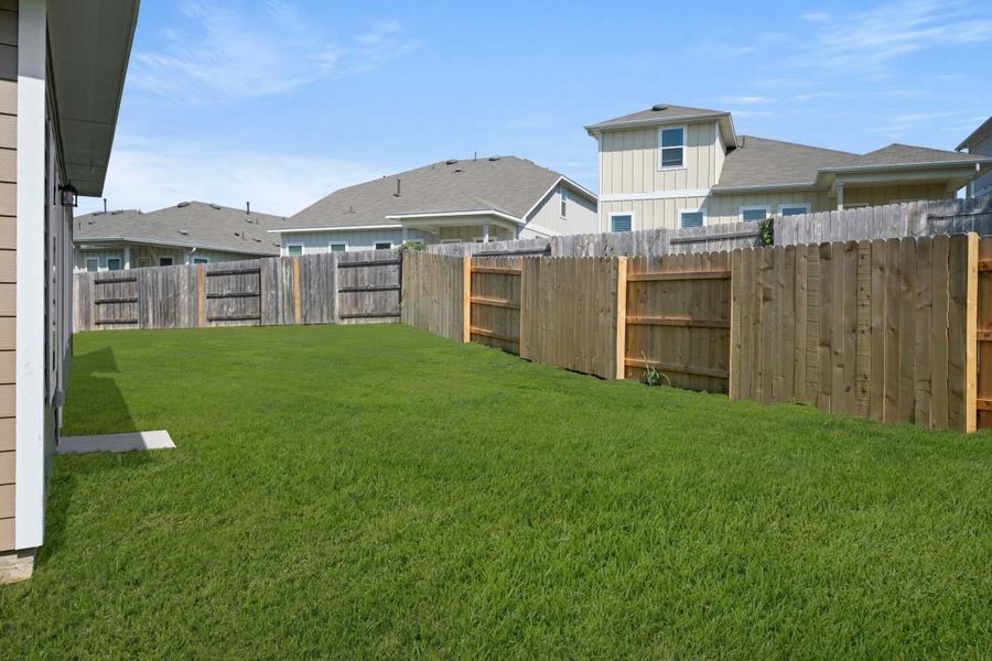 Backyard with green grass and brown fence.