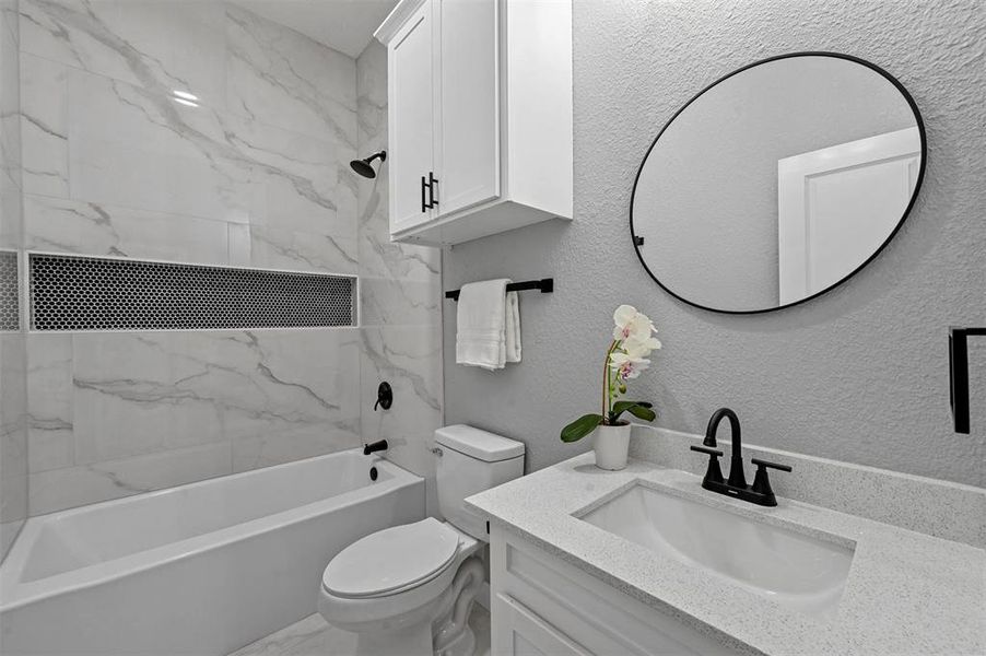 Full bathroom with toilet, tiled shower / bath, and vanity