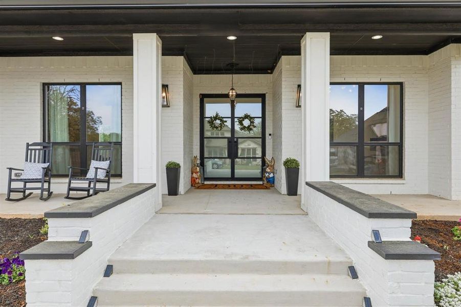 View of exterior entry with a porch and brick siding