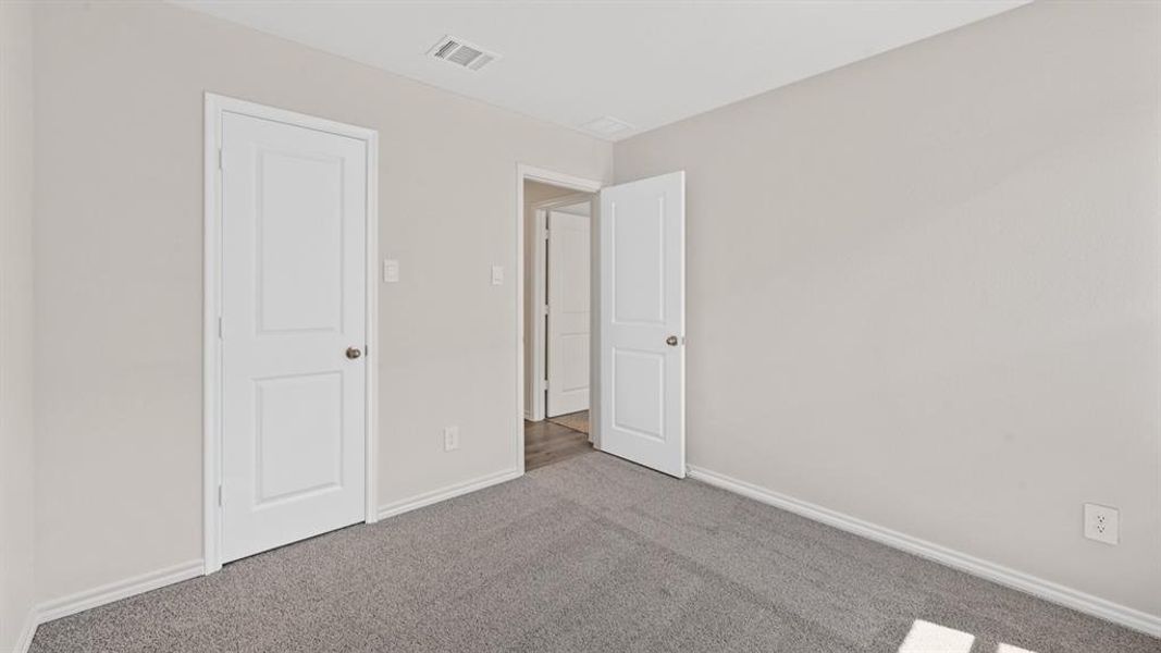 Interior room featuring light gray walls, gray carpet, white baseboards, and white paneled doors with brushed nickel hardware