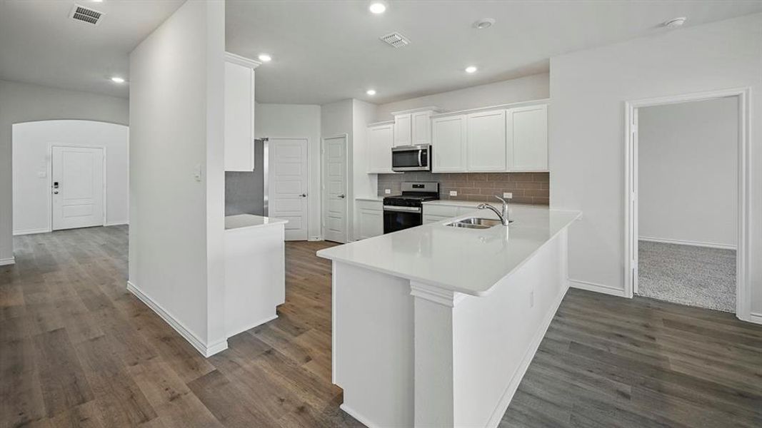 Contemporary kitchen featuring white cabinetry, a large center island with a sink, stainless steel appliances, and a tiled backsplash