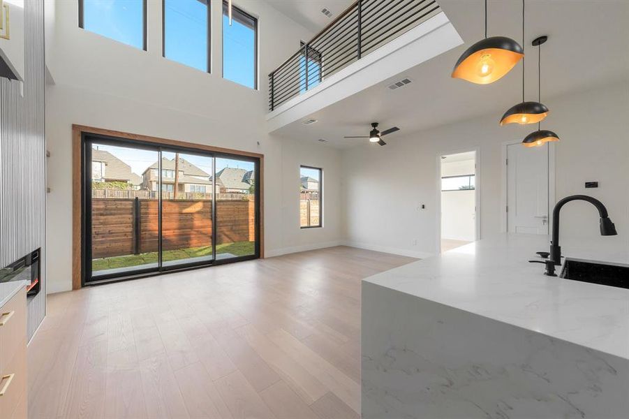 Unfurnished living room featuring light wood finished floors and a high ceiling Unfurnished living room featuring light wood finished floors and a high ceiling