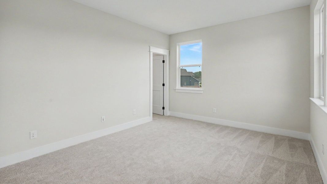 Secondary bedroom with windows and carpet