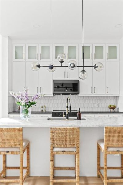 Kitchen with a kitchen bar, light hardwood / wood-style flooring, light stone countertops, and white cabinetry