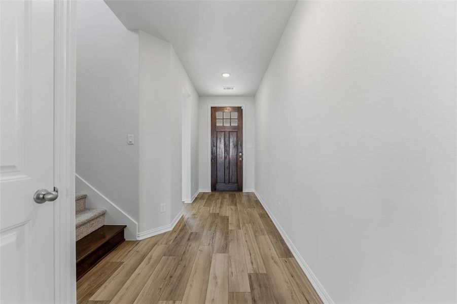 Doorway to outside with wood finished floors, stairway, and recessed lighting