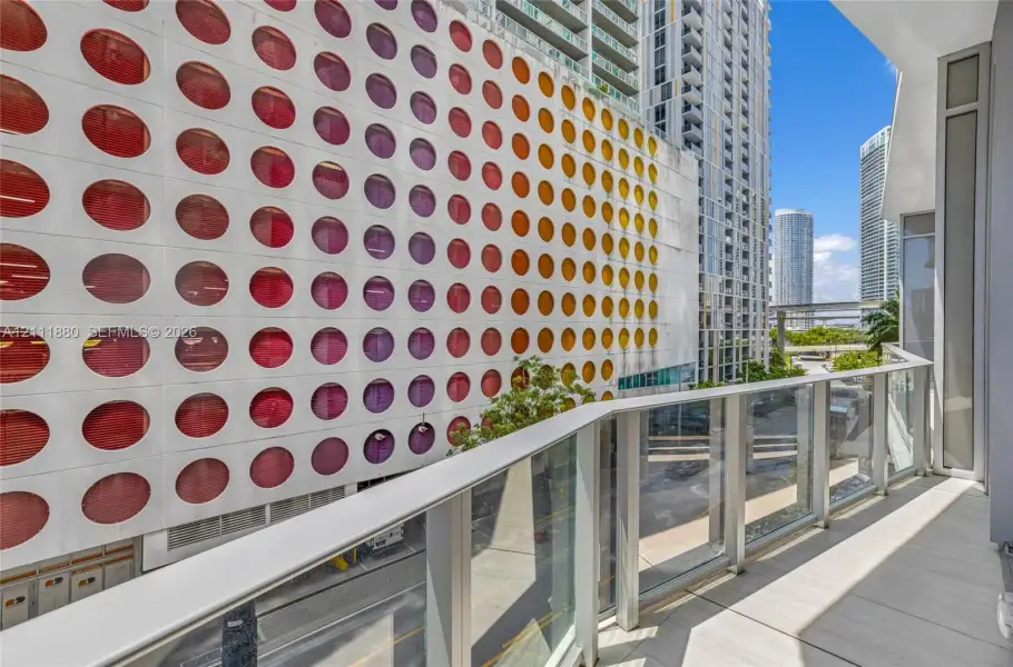 Covered balcony featuring glass paneled railings and light-toned tile flooring
