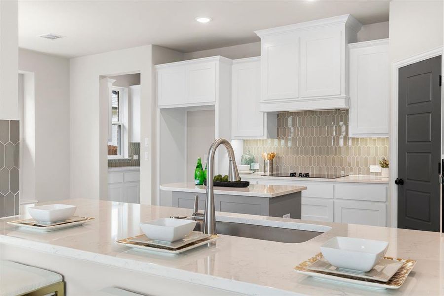 Kitchen with sink, white cabinetry, tasteful backsplash, and light stone countertops