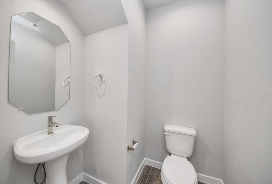 This half bathroom features a stylish pedestal sink, modern hardware, and bright recessed lighting, creating a sleek and inviting space. Sample photo of completed home with similar floor plan. Actual colors and selections may vary. This half bathroom features a stylish pedestal sink, modern hardware, and bright recessed lighting, creating a sleek and inviting space. Sample photo of completed home with similar floor plan. Actual colors and selections may vary.