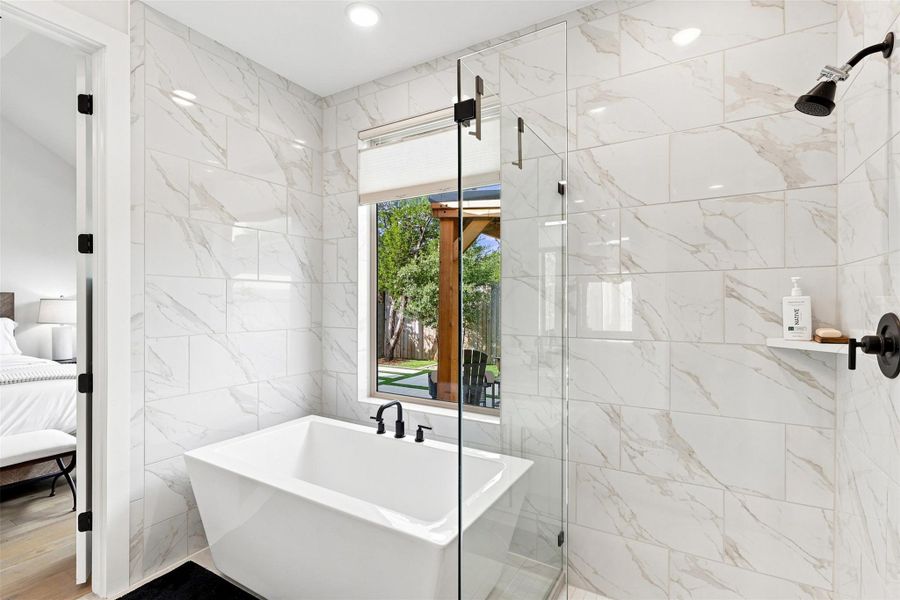 Polished tile walls surround a freestanding soaking tub and a glass-enclosed walk-in shower.