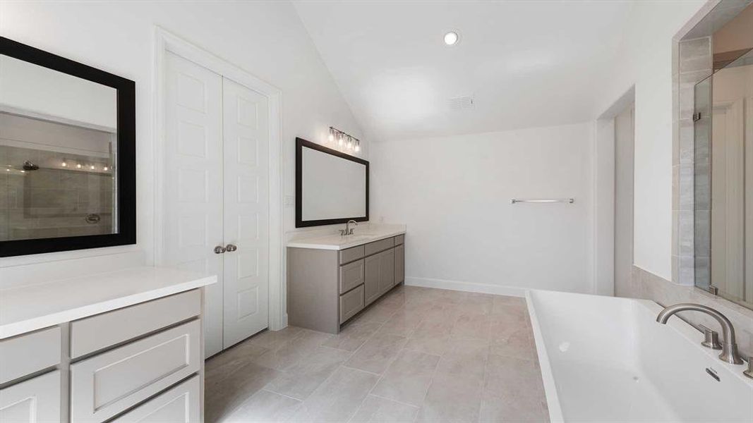 Bathroom featuring vanity, lofted ceiling, a shower with shower door, and tile patterned flooring