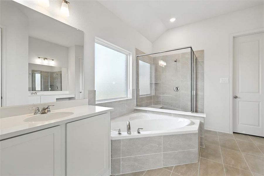 Bathroom featuring a stall shower, vanity, light tile patterned flooring, a bath, and lofted ceiling