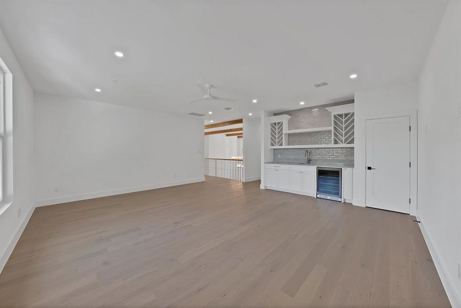 Spacious room featuring wood-finish flooring, recessed lighting, and a contemporary ceiling fan