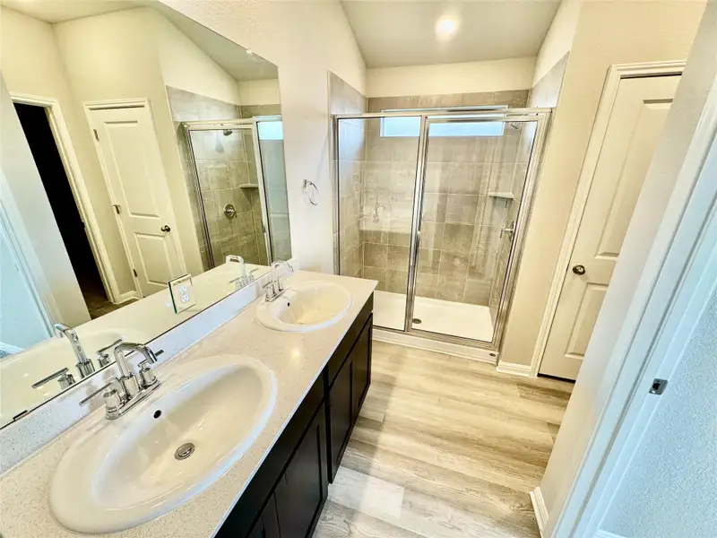 Full bath with a shower stall, light wood-style floors, and double vanity Full bath with a shower stall, light wood-style floors, and double vanity