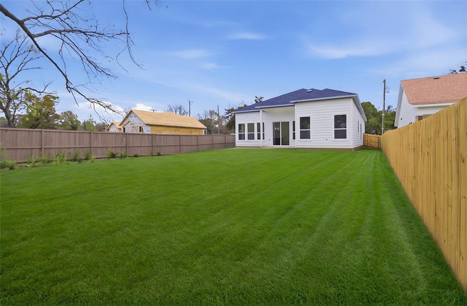Rear view of property with a fenced backyard, roof with shingles, and a patio