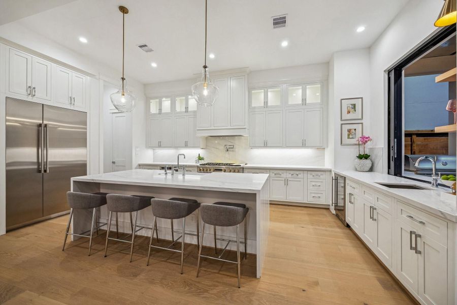 Island Kitchen with Breakfast Bar Seating, Slab Quartz Counter/Side Returns, Two Possini Euro Glass Modern Pendants.  There is an Incredible Appliance Package Including: GE Profile Slide-In Range with 6 Burners, Griddle and Double Ovens. There is also a Hood with a GE Profile Stainless Steel Liner, a GE Profile Drawer Microwave, GE Profile Panel Ready Built-In Dishwasher. Also included is a GE Profile Panel Ready Refrigerator/Freezer.