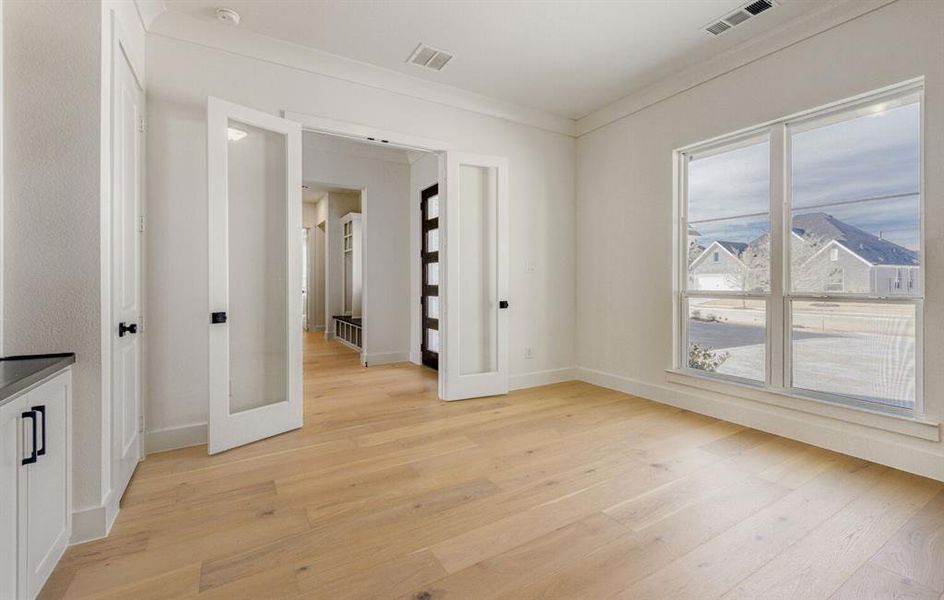 Unfurnished room with light wood finished floors and ornamental molding