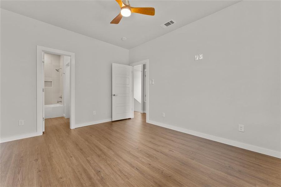 Unfurnished bedroom with light wood-style flooring, ceiling fan, and connected bathroom Unfurnished bedroom with light wood-style flooring, ceiling fan, and connected bathroom