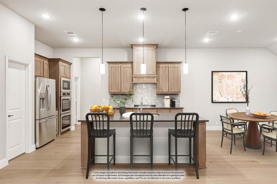 Kitchen with light wood cabinets, center island with three bar stools, pendant lights, and stainless steel appliances