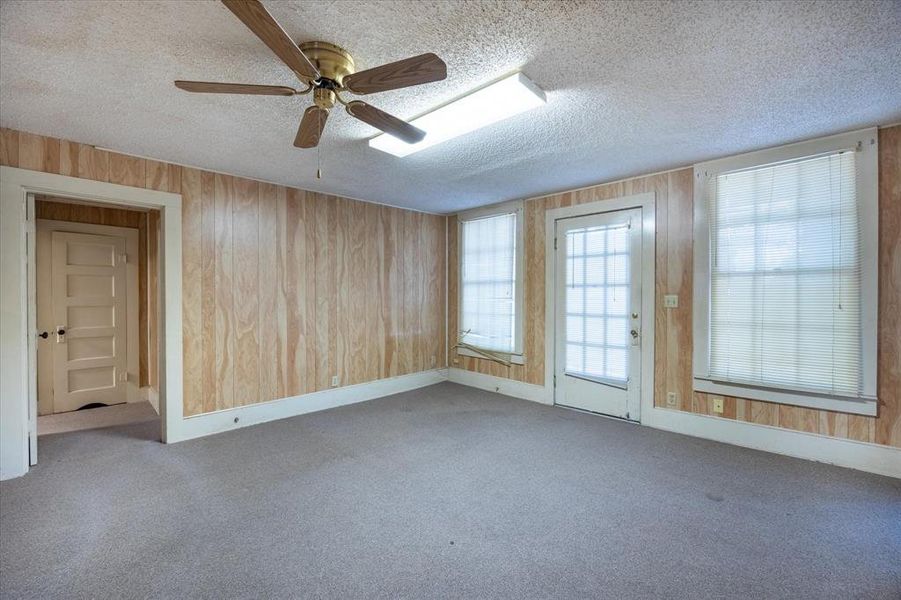 Empty room with ceiling fan, a textured ceiling, and light colored carpet