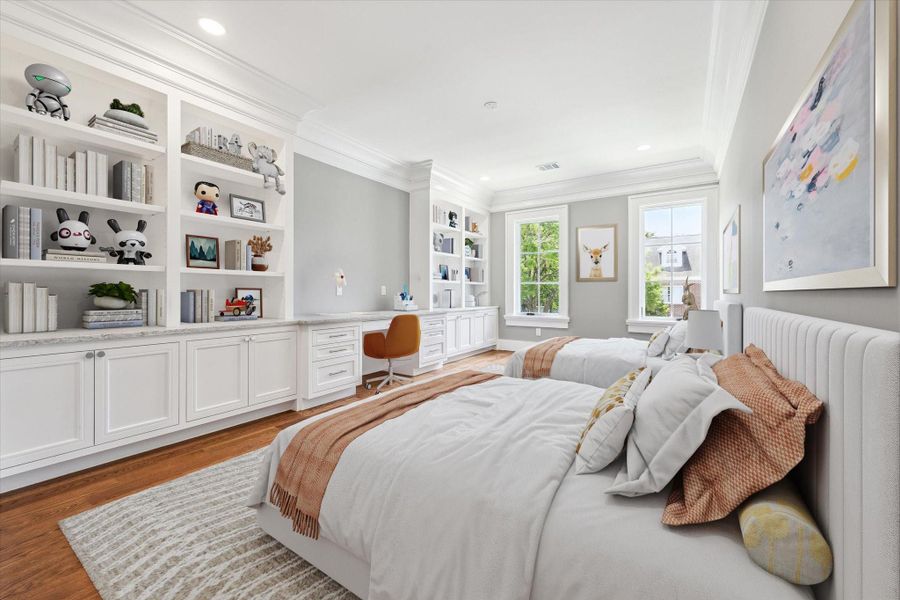 This bright and spacious bedroom features two twin beds, built-in shelving with lots of storage, and a desk area. The large windows provide plenty of natural light, complementing the elegant crown molding and warm wood flooring. There is also a large walk-in closet and an en-suite bath.  This photo has been virtually staged.