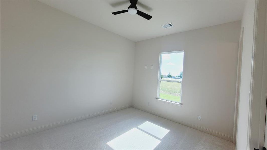Neutral toned walls with carpeting, a single window, and a ceiling fan