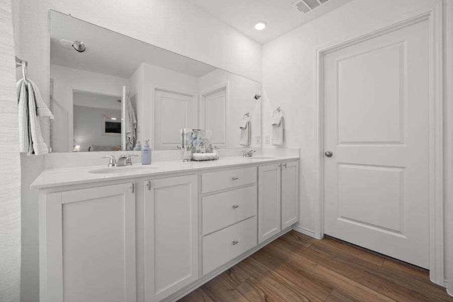 A well-appointed primary bathroom features a long vanity with dual sinks, ample storage, and rich LVP woodgrain flooring. A well-appointed primary bathroom features a long vanity with dual sinks, ample storage, and rich LVP woodgrain flooring.