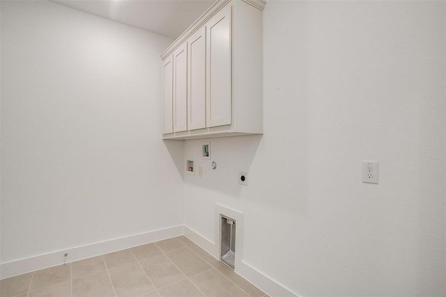 Laundry room with hookup for a gas dryer, cabinets, washer hookup, light tile floors, and hookup for an electric dryer