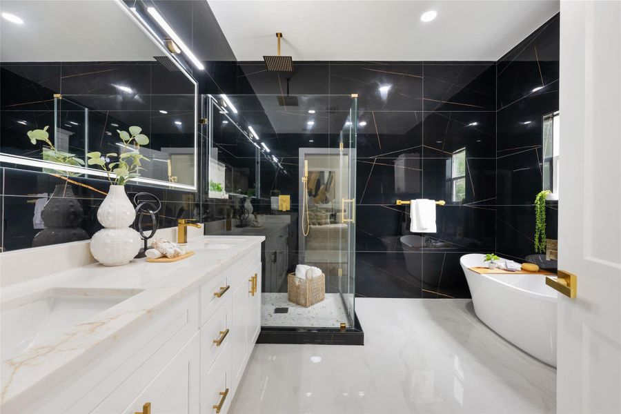 Spacious bathroom featuring a freestanding soaking tub, walk-in shower with glass enclosure, dual vanity with undermount sinks, black tiled walls with gold veining, and light-toned flooring