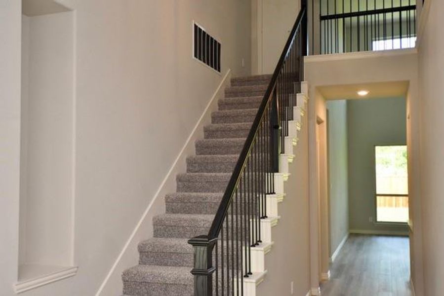 Stairway with wood finished floors and a high ceiling