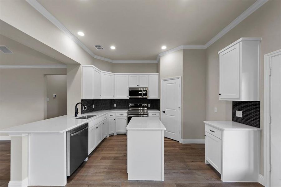 Modern kitchen featuring white cabinetry, light-toned countertops, and a dark tile backsplash